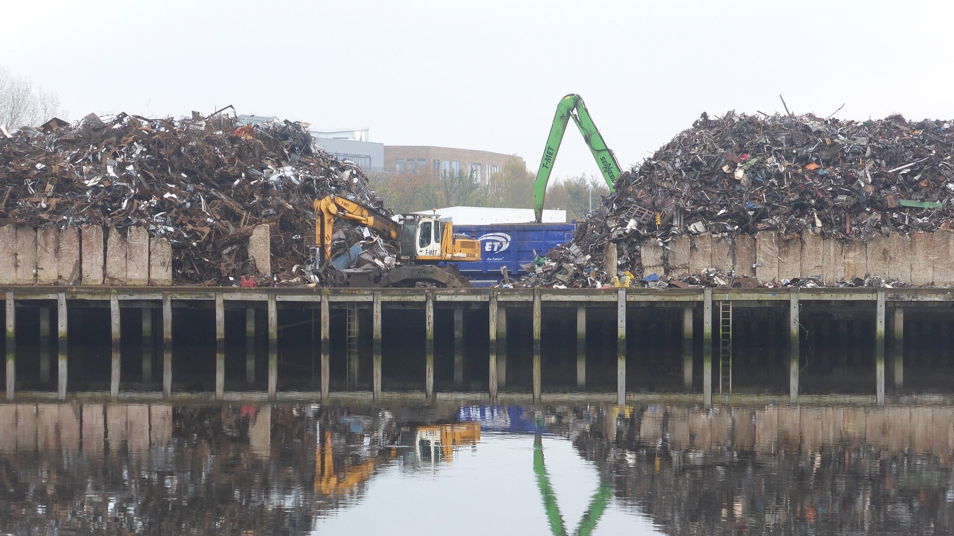 Scrap metal yard with large piles and a material handler